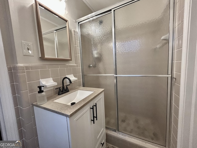 full bathroom with vanity, backsplash, a shower stall, and tile walls