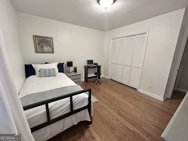 bedroom with a closet, wood finished floors, and baseboards