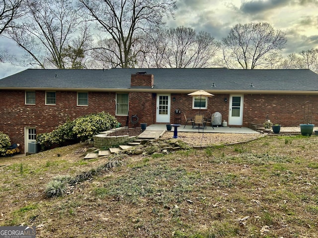 back of house with a patio area, a chimney, cooling unit, and brick siding