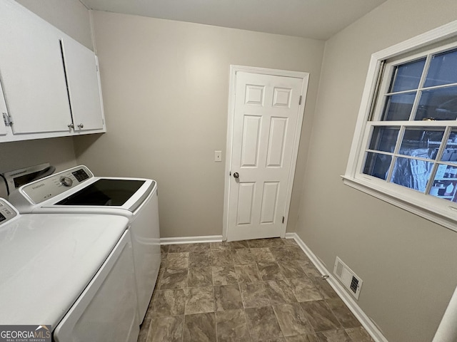 laundry room with washing machine and dryer, visible vents, cabinet space, and baseboards