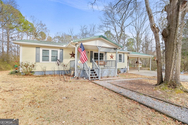 view of front facade featuring metal roof, driveway, a porch, and an attached carport