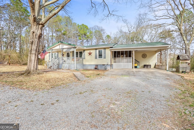 manufactured / mobile home with metal roof, an attached carport, gravel driveway, crawl space, and a porch