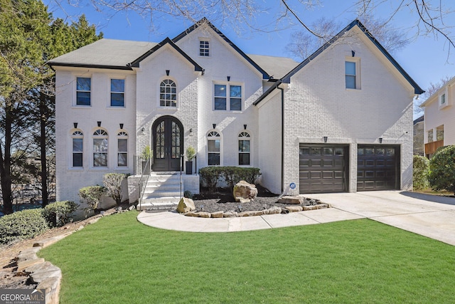 french provincial home with a garage, concrete driveway, french doors, a front lawn, and brick siding