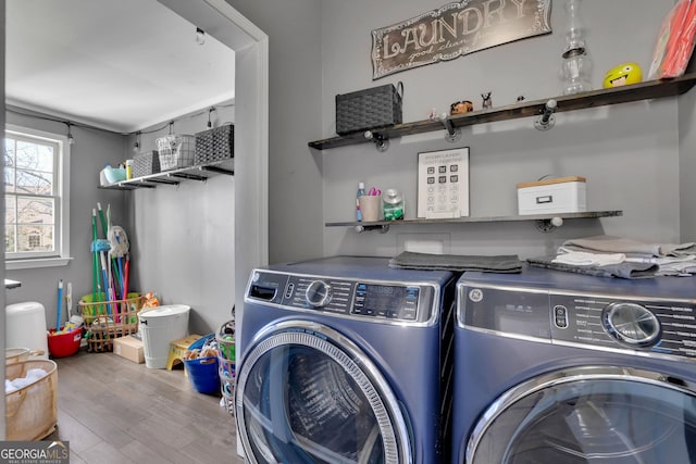 laundry area featuring laundry area, washing machine and clothes dryer, and wood finished floors