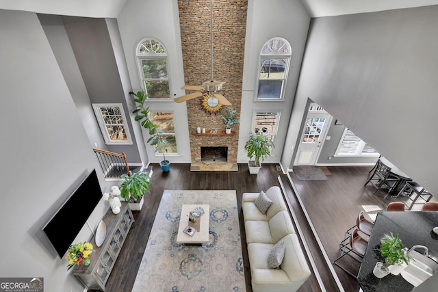 living room with a fireplace, stairway, a towering ceiling, ceiling fan, and wood finished floors