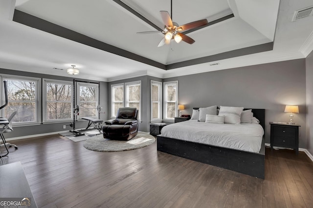 bedroom featuring visible vents, baseboards, ornamental molding, wood-type flooring, and a raised ceiling