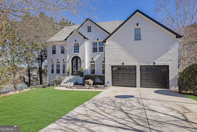 french country home featuring a garage, concrete driveway, brick siding, and a front lawn