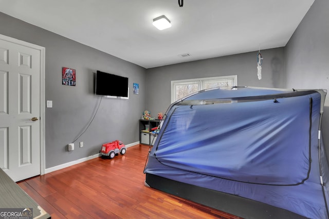 recreation room with wood finished floors, visible vents, and baseboards