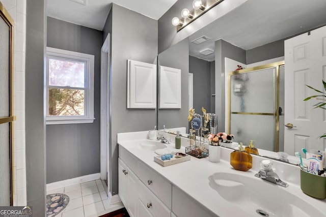 full bath with double vanity, a stall shower, a sink, tile patterned flooring, and baseboards