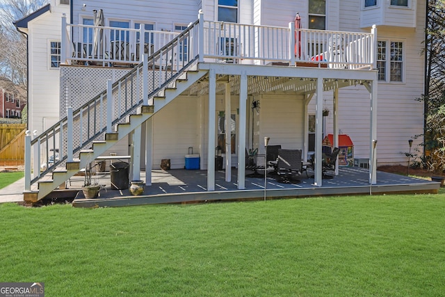 back of property with a deck, a lawn, and stairway