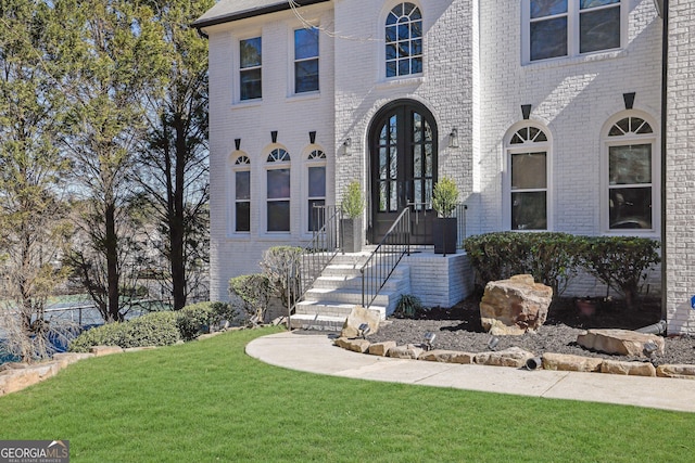 view of front of house with a front yard, french doors, and brick siding