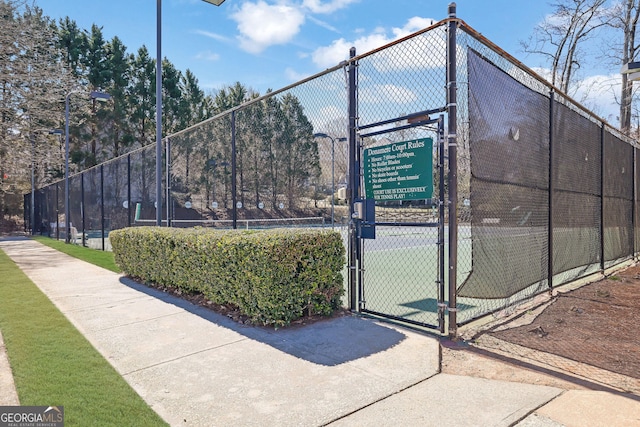 view of tennis court with a gate and fence