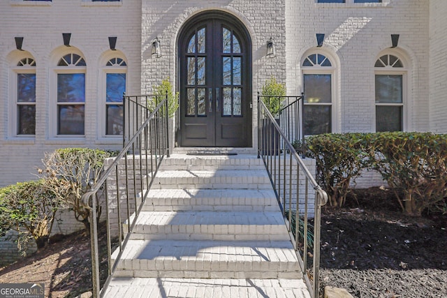 view of exterior entry with brick siding and french doors