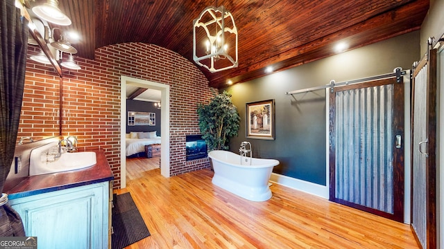 interior space with wood ceiling, a brick fireplace, brick wall, and wood finished floors