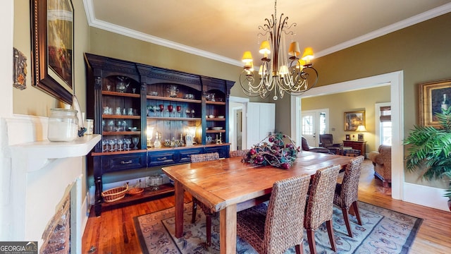 dining space with ornamental molding, wood finished floors, and a notable chandelier