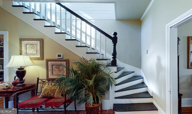 stairway featuring crown molding, baseboards, and wood finished floors