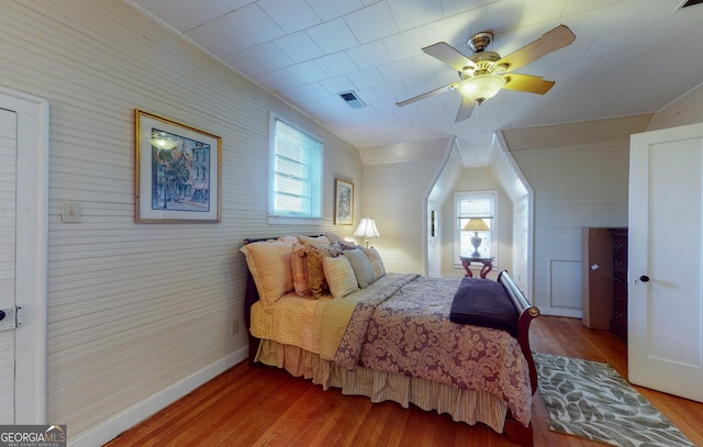 bedroom featuring a ceiling fan, visible vents, baseboards, and wood finished floors