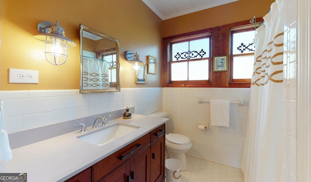 full bath with tile patterned flooring, toilet, vanity, tile walls, and wainscoting