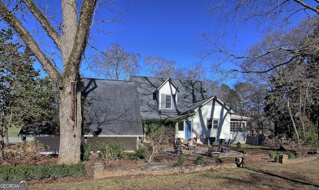 view of front of property featuring a shingled roof and a patio area