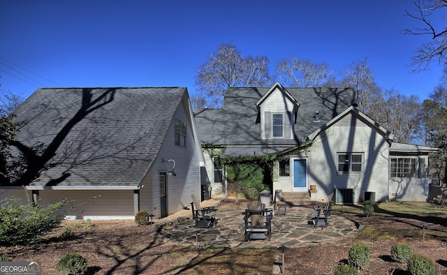 view of front of home featuring a patio, a shingled roof, central AC unit, entry steps, and a fire pit