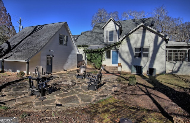 rear view of house featuring entry steps, central AC unit, roof with shingles, a patio area, and brick siding