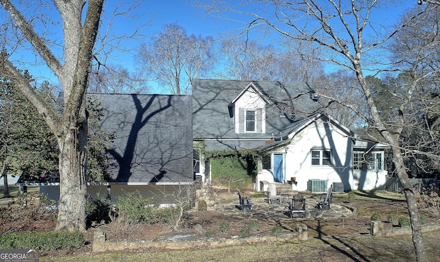 view of front of home with central AC unit and roof with shingles