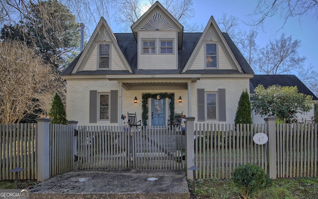 view of front facade featuring a fenced front yard, covered porch, brick siding, and a gate