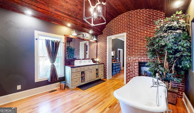 bathroom with visible vents, lofted ceiling, wood ceiling, wood finished floors, and a freestanding tub