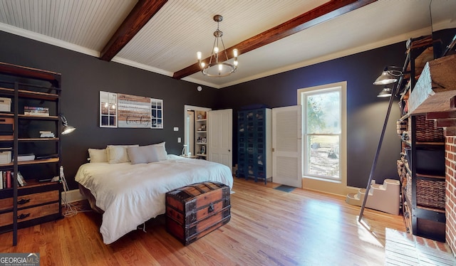 bedroom with a notable chandelier, wood finished floors, baseboards, ornamental molding, and beamed ceiling