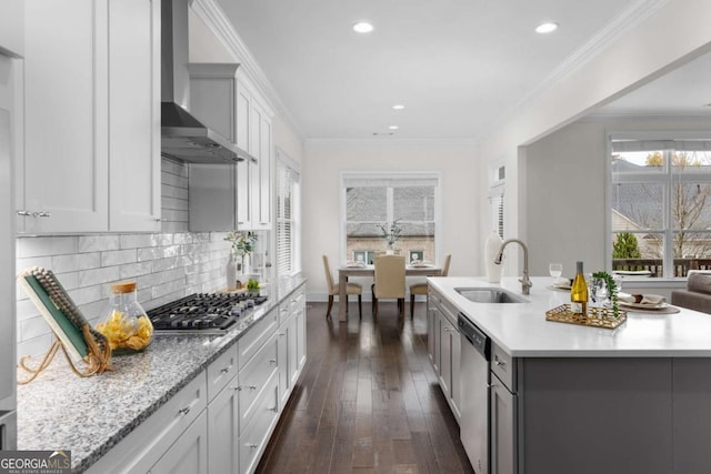 kitchen featuring ornamental molding, appliances with stainless steel finishes, wall chimney exhaust hood, and a sink