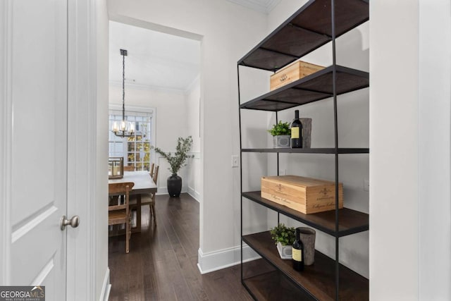 corridor with dark wood finished floors, a chandelier, baseboards, and ornamental molding