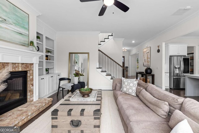 living area with dark wood-style floors, stairway, a brick fireplace, and built in features