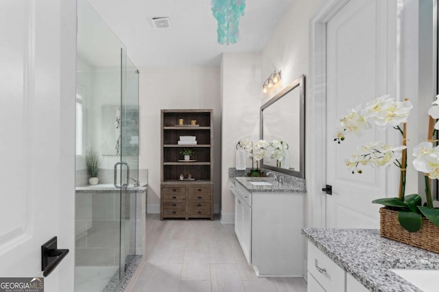 full bathroom with tile patterned floors, two vanities, a stall shower, a sink, and baseboards