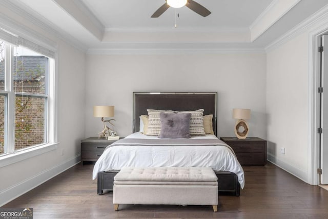 bedroom with wood finished floors, a raised ceiling, and baseboards