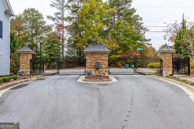 view of street featuring a gated entry, curbs, and a gate