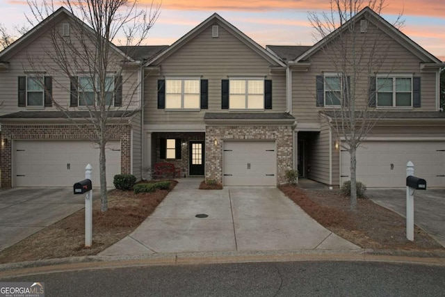 multi unit property with driveway, an attached garage, and brick siding