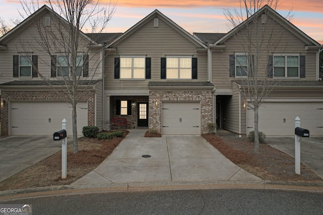 view of property featuring driveway, a garage, and brick siding