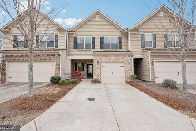 townhome / multi-family property featuring a garage, driveway, and brick siding