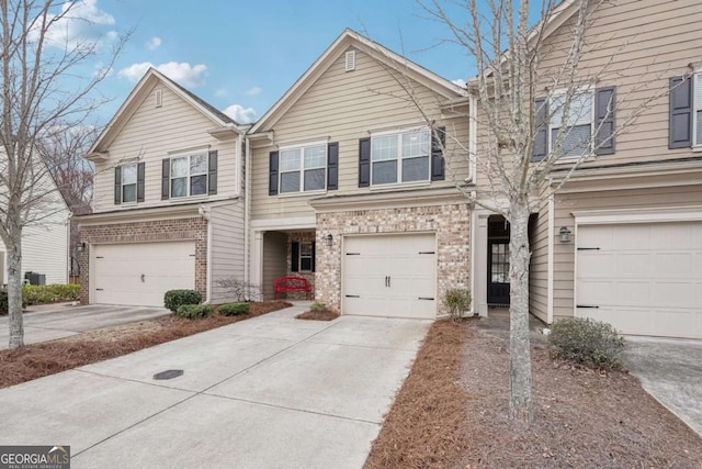 townhome / multi-family property featuring driveway, brick siding, and an attached garage