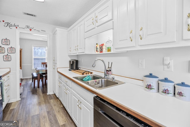 kitchen with white cabinets, a sink, visible vents, and dishwasher