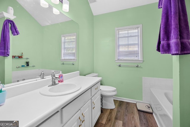 full bathroom with toilet, wood finished floors, vanity, baseboards, and a bath