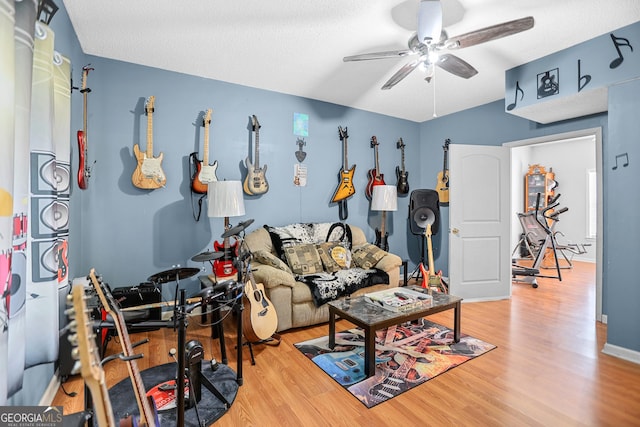 living area with wood finished floors, a ceiling fan, and baseboards