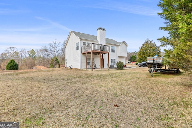 back of property featuring a deck, a yard, a chimney, and central air condition unit