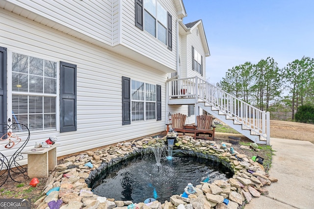 view of side of home with a small pond and stairway