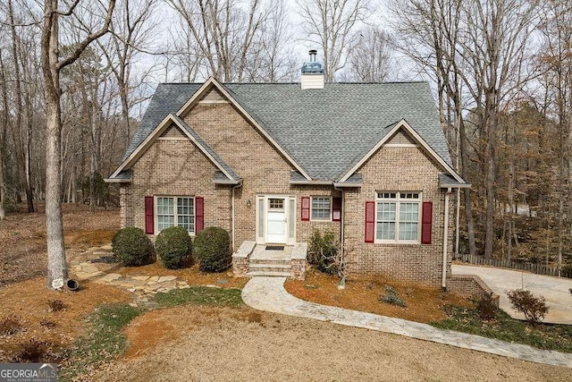 view of front facade featuring brick siding, roof with shingles, and a chimney