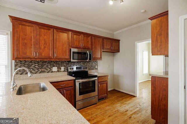 kitchen featuring ornamental molding, stainless steel dishwasher, light wood-style floors, and decorative backsplash