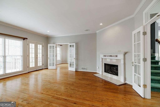 unfurnished living room featuring a high end fireplace, french doors, and wood finished floors