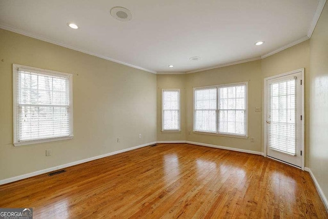 spare room with light wood-style flooring, visible vents, baseboards, and ornamental molding