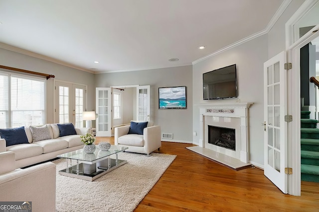 living area featuring recessed lighting, stairway, wood finished floors, ornamental molding, and french doors