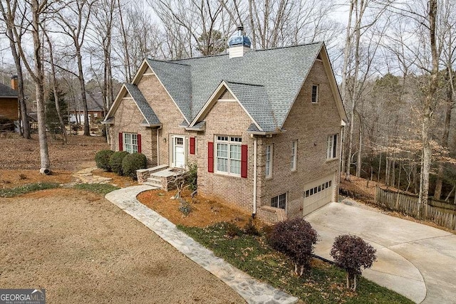 view of front of home with driveway, a chimney, brick siding, an attached garage, and a shingled roof